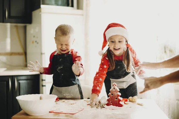 迷人的小男孩和女孩在厨房的桌子上准备圣诞节和母亲做饼干 — 图库照片