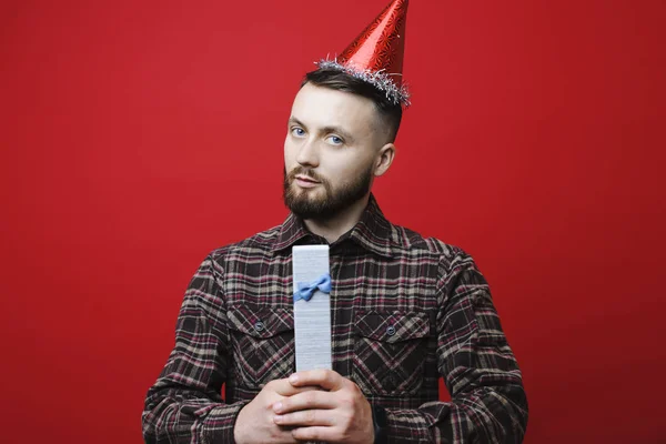 Atrakcyjne Młody Człowiek Party Hat Patrząc Kamery Trzymając Urodzinowa Niespodzianka — Zdjęcie stockowe
