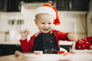 Sevimli çocuk önlük ve çerez kesici ve un ile mutfakta kırmızı Santa şapka