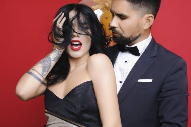 Yakışıklı sakallı erkek takım elbise Abiye balonlar kırmızı zemin üzerine avuç yakın dururken baştan çıkarıcı kadın bakarak