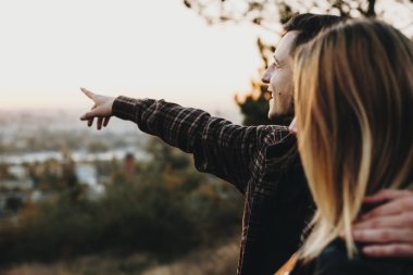 Yakışıklı genç adam kız arkadaşı kucaklayan ve doğa bulanık arka plan üzerinde birlikte ayakta iken mesafede işaret yan görünüm