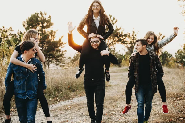 Three Young Men Giving Piggyback Ride Lovely Girlfriends While Walking — Stock Photo, Image