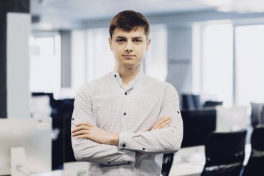 Yakışıklı genç erkek geçti ve kamera Office bulanık arka plan üzerinde dururken bakarak silah tutmak. Kendine güvenen adam ofiste ayakta