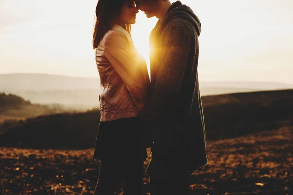 作物の若い男と女の素晴らしい田園地帯と美しい日没の空の背景の上に立っている間鼻に触れることの側面図です 夕焼け空に夫婦が作物 — ストック写真