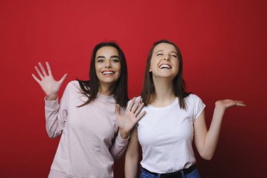 Eğleniyor iki şaşırtıcı kız portre Studio kırmızı bir duvara gülüyor.