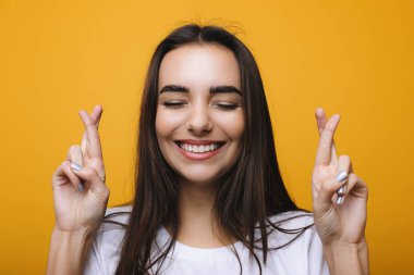 İnanılmaz beyaz kadın bir dilek kenetlenmiş parmaklar ve cheches dişler sarı bir arka plan önünde yapma. Gerçekten kazanmak istiyor.