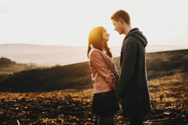 Yan görünüm portre seyir bir başka bir gülümseyen için ve onların tatil zamanlarında seyahat ederken gündoğumu önünde elele şaşırtıcı bir çiftin.