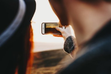 Seyahat ve tatil zamanında yeni yerler keşfetmek süre günbatımında bir panorama onların smartphone ile yapıyor kucaklayan genç mutlu çift.