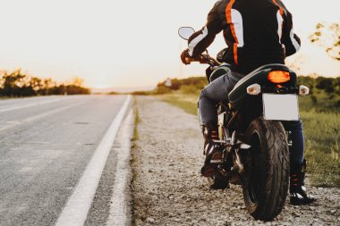 Bir motorcu kırpma görünümünü Onun Bisiklet yolun karşı günbatımı macera zamanının yakın başlatmak hazırlanıyor seyahat ederken arka.