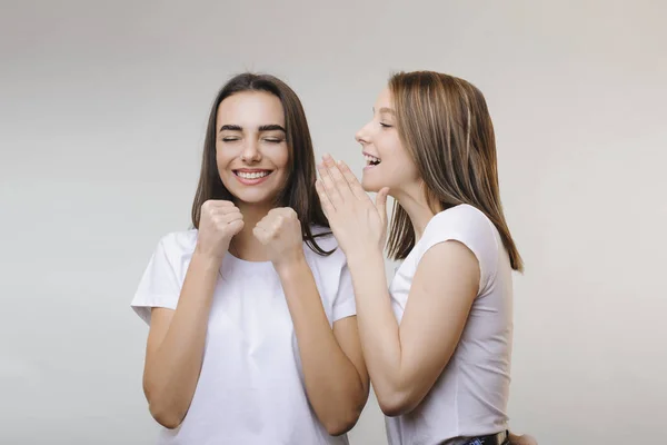 Two lovely women gossiping while one is telling something to ano