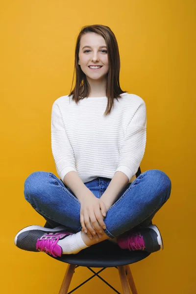 Schöne junge kaukasische Frau sitzt auf einem Stuhl mit gekreuzten Bein — Stockfoto