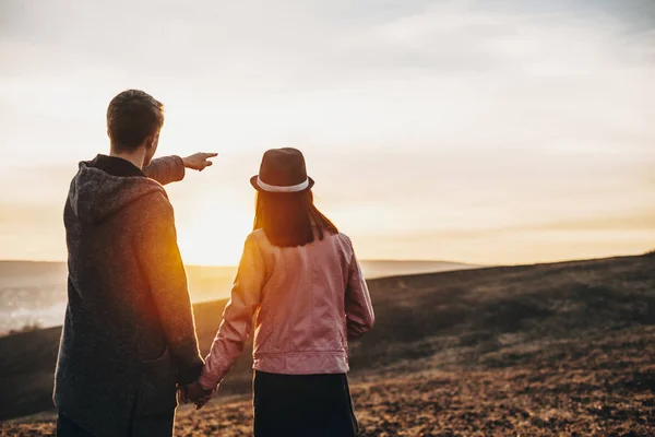 Vista trasera de una joven pareja viajando alrededor del mundo mientras el hombre — Foto de Stock