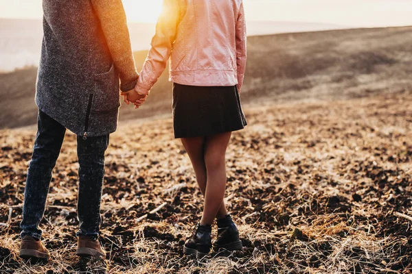 Vista de la cosecha de las piernas de pareja y la mano de celebración contra la puesta del sol mientras d —  Fotos de Stock