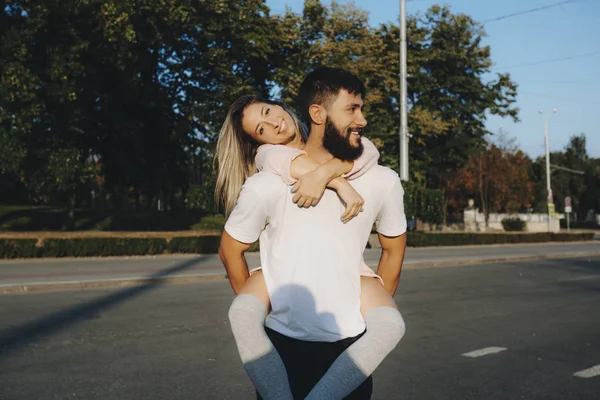 Schöne junge kaukasische Paar Spaß haben, während Mädchen ist huckepack — Stockfoto