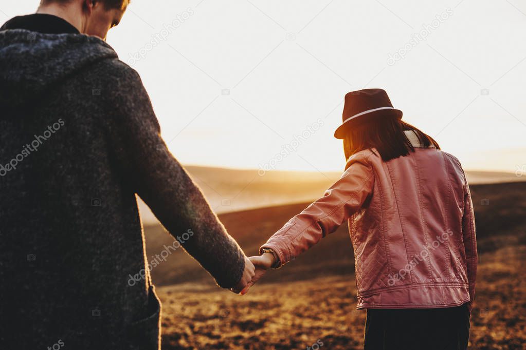 Back view of a caucasian couple holding by hands and traveling w