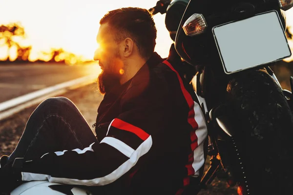 Incrível barbudo masculino motociclista inclinado em sua bicicleta perto da estrada aga — Fotografia de Stock