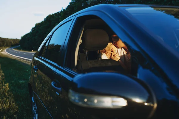 Amazing caucasian couple kissing on the back bench of the car wh