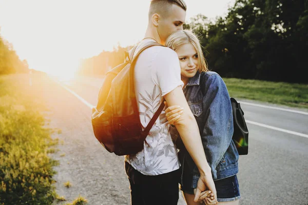 Adorável casal caucasiano com mochilas abraçando enquanto a menina é l — Fotografia de Stock