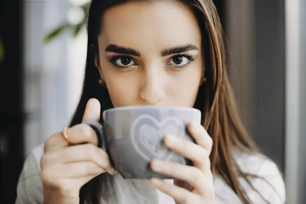 Primer plano retrato de una atractiva morena bebiendo café mientras — Foto de Stock