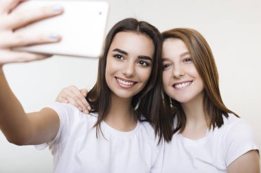 Beyaz giyinmiş iki güzel genç kadın smilin selfie yapıyor