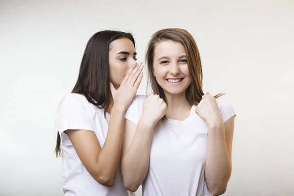 Bella giovane femmina caucasica raccontando un segreto alla sua ragazzafri — Foto Stock