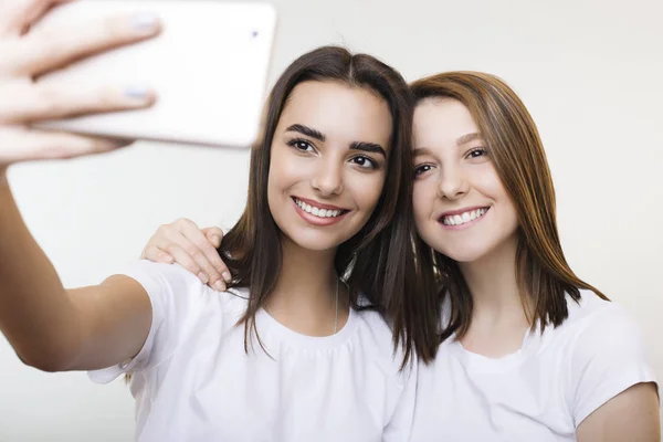 Beyaz giyinmiş iki güzel genç kadın smilin selfie yapıyor — Stok fotoğraf