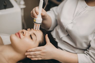 Yüzünde bir kozmetolojist tarafından bir spa salonunda mezoterapi yapan hoş bir kafkas kadının yan görünüm portresi.