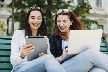 Bir tablet ekranına bakarken gülen iki güzel kadın