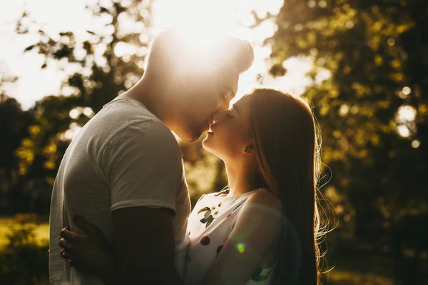 Vista lateral retrato de um casal incrível beijando contra o pôr do sol ou — Fotografia de Stock