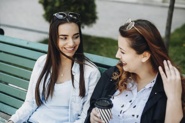 Zwei junge kaukasische Frauen sprechen lächelnd, während sie auf einem Seil sitzen — Stockfoto