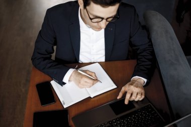Upper view of a male hands working while a hand holding a pen on clipart