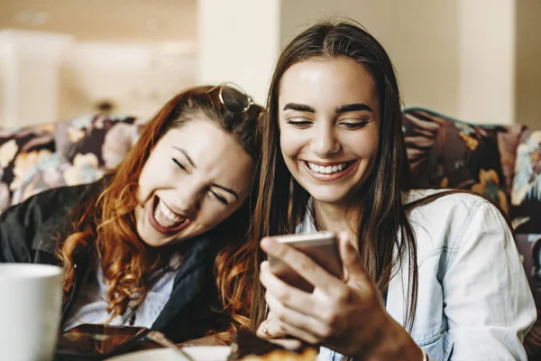 Bella giovane femmina che tiene uno smartphone ridendo mentre showi — Foto Stock