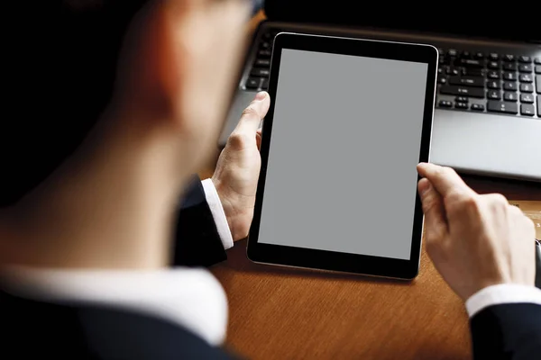 Mãos masculinas usando um tablet enquanto sentado em uma mesa com um laptop — Fotografia de Stock