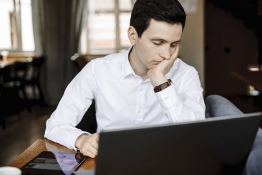 Young caucasian worker falling asleep while working at his lapto clipart