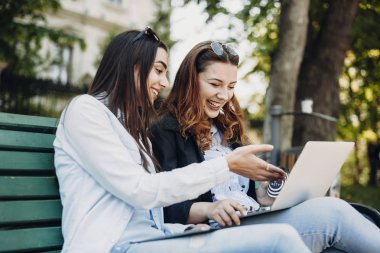 Bir bankta otururken eğlenen iki genç kız arkadaş