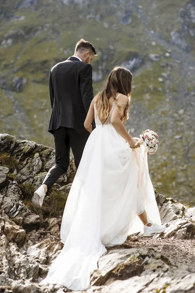 Unerkennbare Braut, die mit einem Eimer in der Hand in den Bergen spaziert — Stockfoto