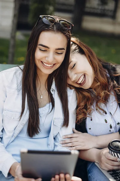 Zwei schöne Frauen haben Spaß beim Lachen, während sie eine Tablette halten — Stockfoto