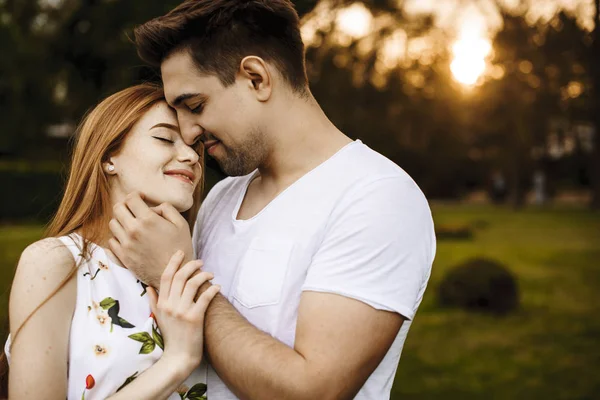 Knappe jonge man omarmt haar vriendin glimlachend en aanraakt — Stockfoto