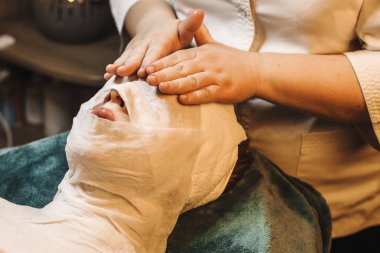 Bir spa yatağına yaslanmış kadın yüz anti-yaş prosedürü yapıyor 