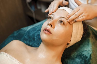 Güzel genç beyaz kadın bir spa yatağına bakarak eğilerek 