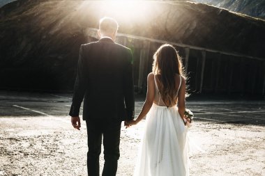 Tanınmayan evli çift güneşlere karşı el ele yürüyor