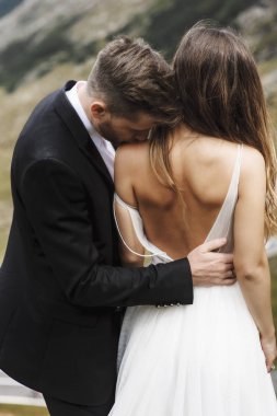 Genç beyaz şık damat omzundan gelinöpüşme.