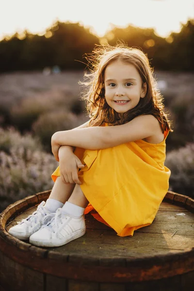 Retrato de uma linda menina sentada em um barril olhando para — Fotografia de Stock