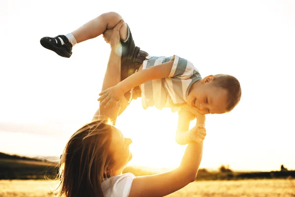 Νέος Καυκάσιος μητέρα παίζει με το γιο του ενάντια στο ηλιοβασίλεμα γέλιο — Φωτογραφία Αρχείου