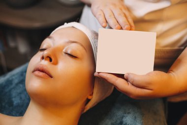 Kozmetik uzmanı elleri ürünün kutusunu gösteriyor.