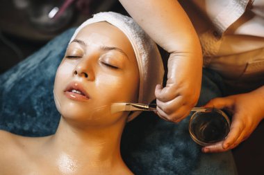 Kozmetik uzmanı elinde Hyaluro 'lu anti yaş maskesi olan bir bardak tutuyor.