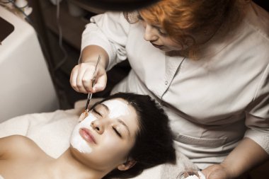 Cazibeli beyaz kadın, gözleri kapalı bir yatağa yaslanıyor.