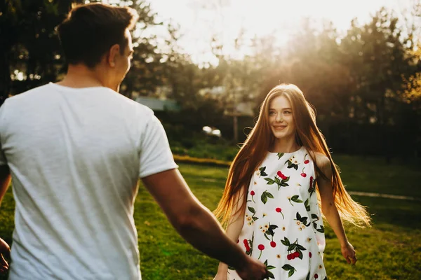 迷人的女人留着长长的红头发 脸上挂着雀斑 一边微笑 一边看着她的男朋友 一边在外面迎着日落和树木跳舞 — 图库照片