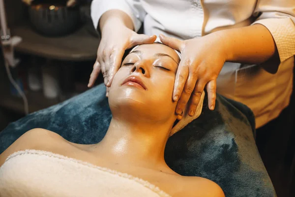 Büyüleyici beyaz kadın, kaplıca yatağına yaslanmış, gözleri kapalı.