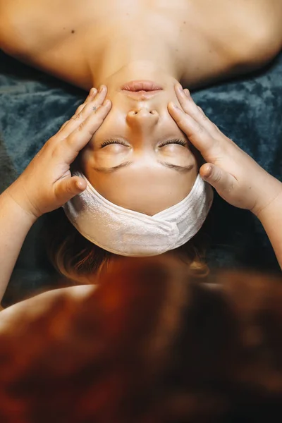 Upper view of a beautiful caucasian woman having facial massage